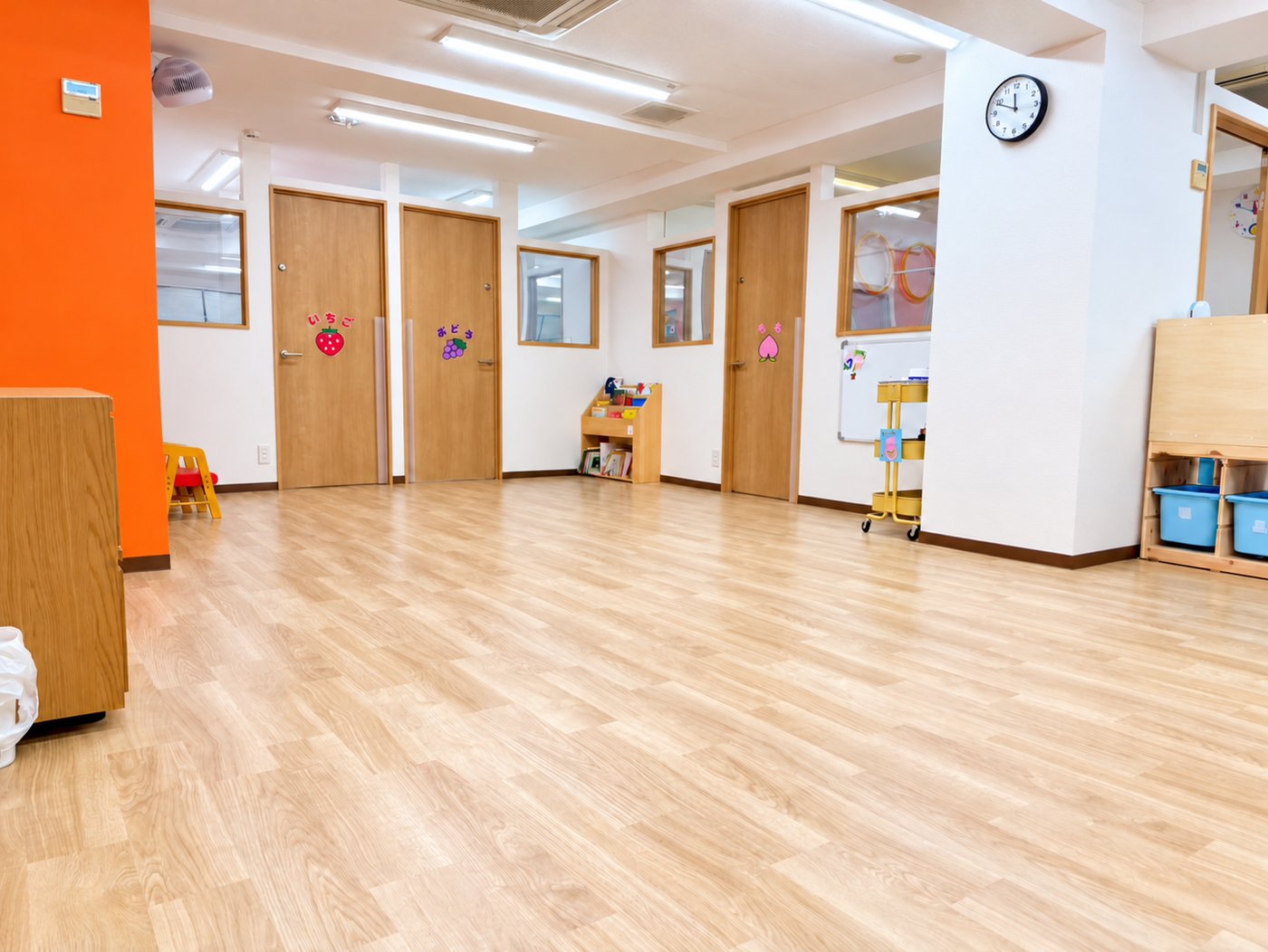 木目の床の明るい大部屋。奥にいちご・ぶどう・もものお部屋の扉が並んでいます